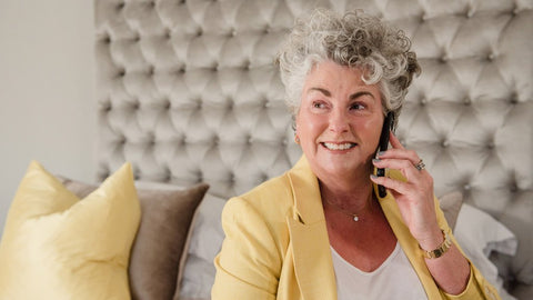 Maxine Laceby entrain de téléphoner tout sourire assise sur un canapé
