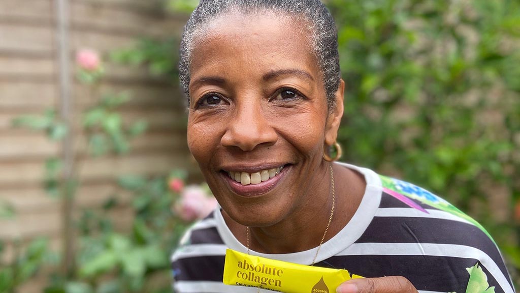 Femme souriante tenant un sachet d'élixir de collagène liquide dans la main